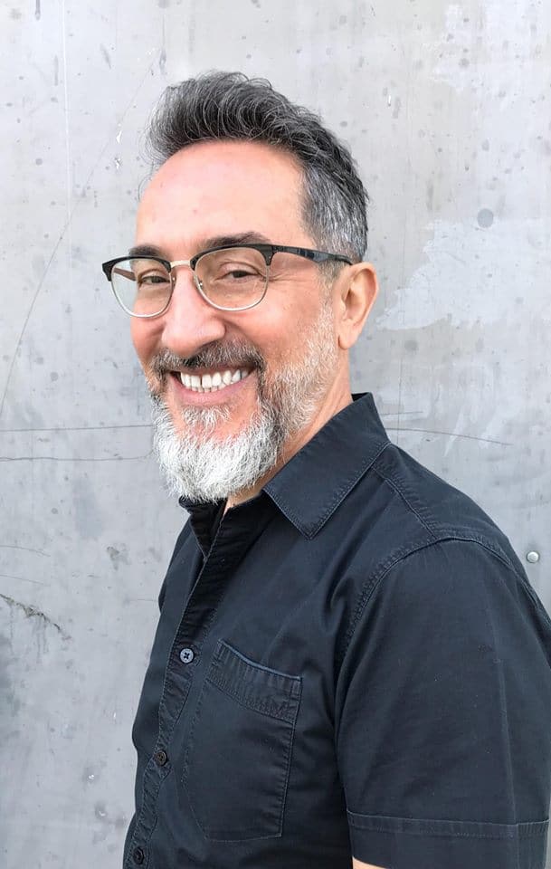 A man with glasses and beard smiling for the camera.