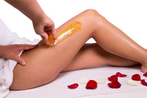 A person waxing their legs with orange wax.